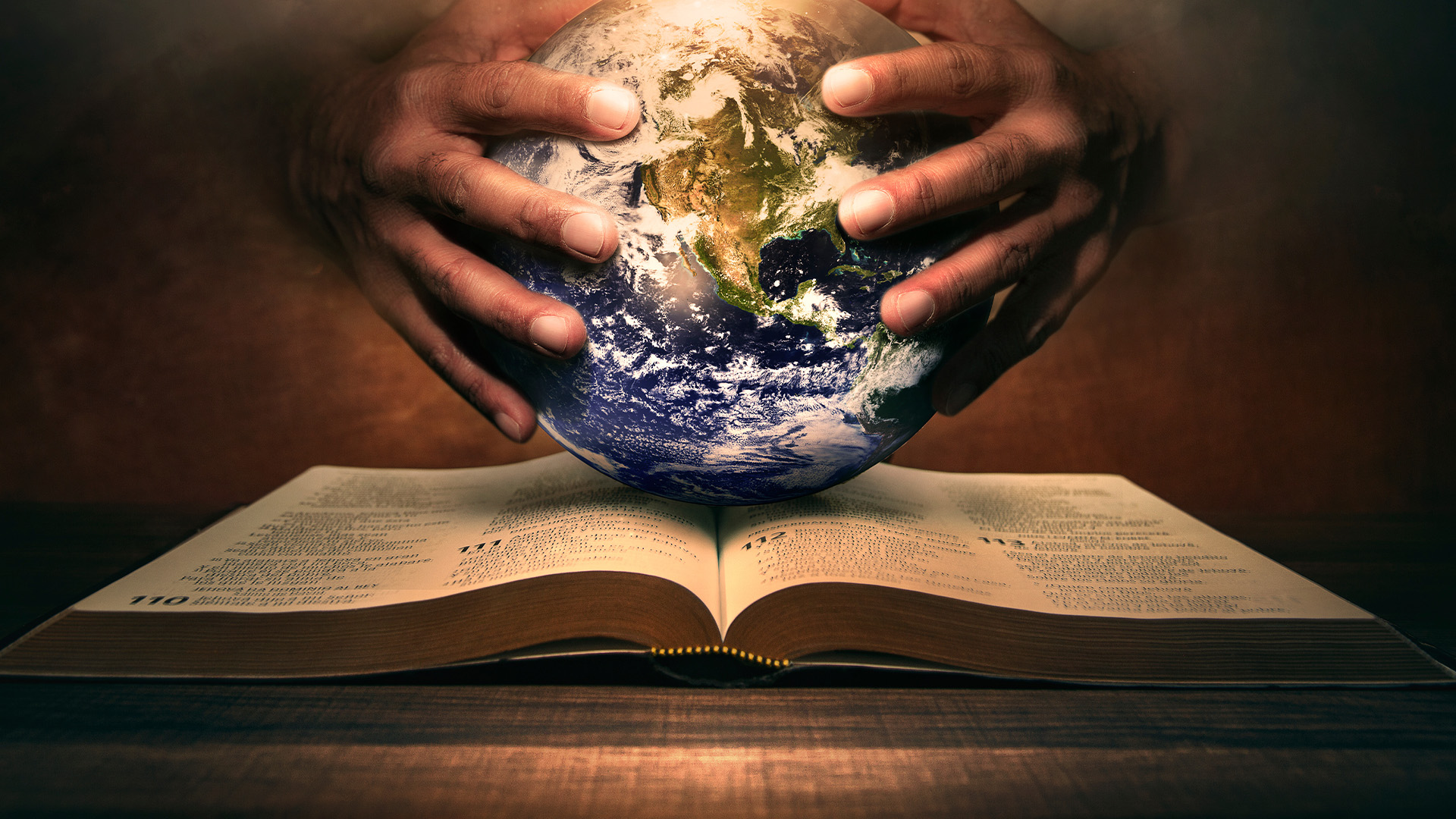 Hands holding a bible with a globe